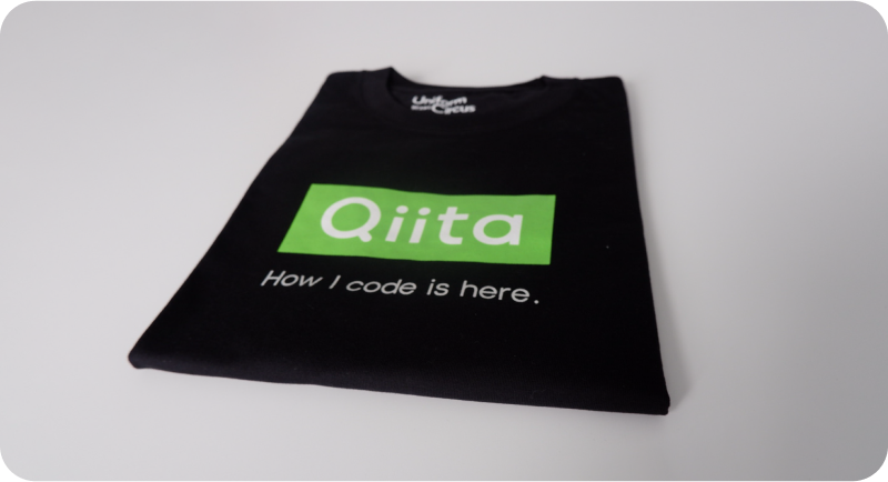 [Qiitaのロゴと、「How I code is her.」という文言がプリントされた黒いTシャツの写真